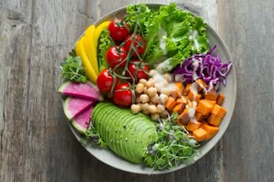 A bowl of lettuce, tomato, and other fresh vegetables